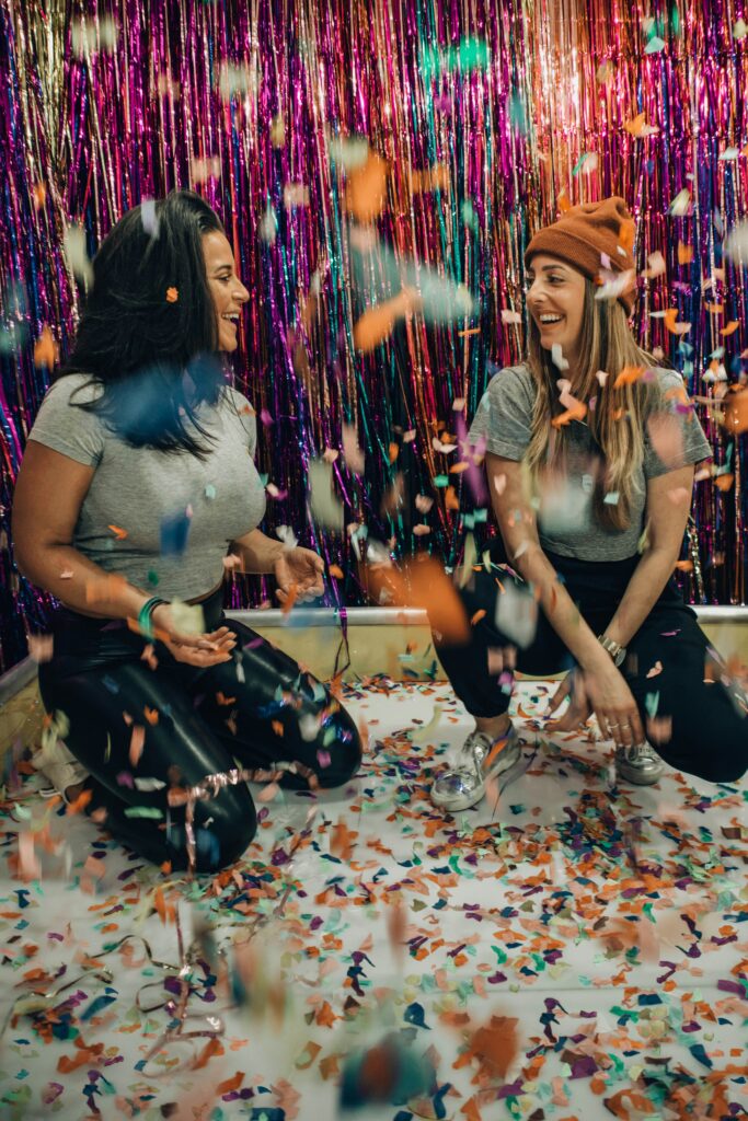 two girls laughing under confetti
